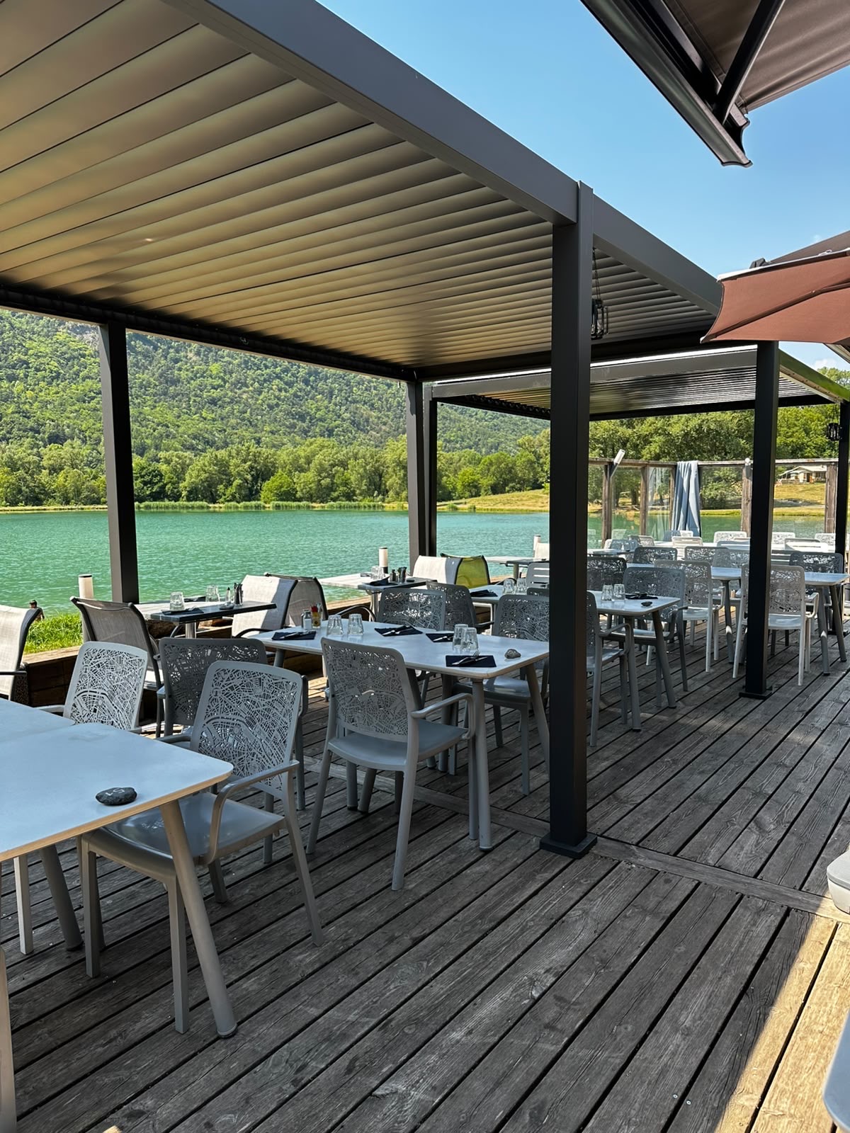 La terrasse en bois sous la pergola face au lac turquoise